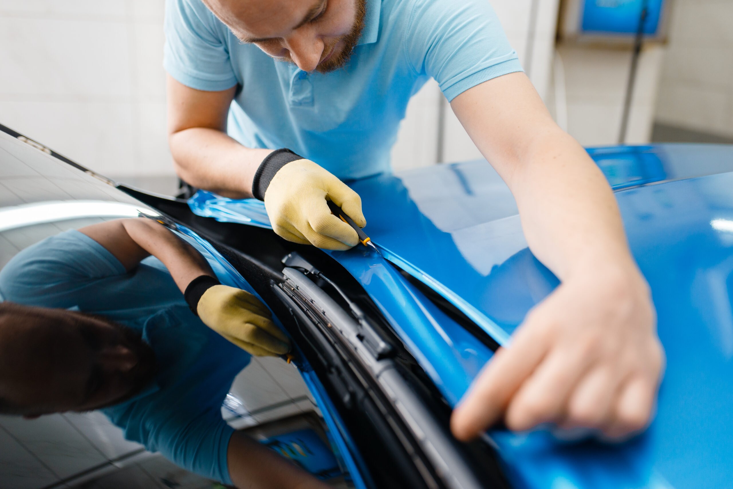 Car wrapping, man cuts protective foil or film